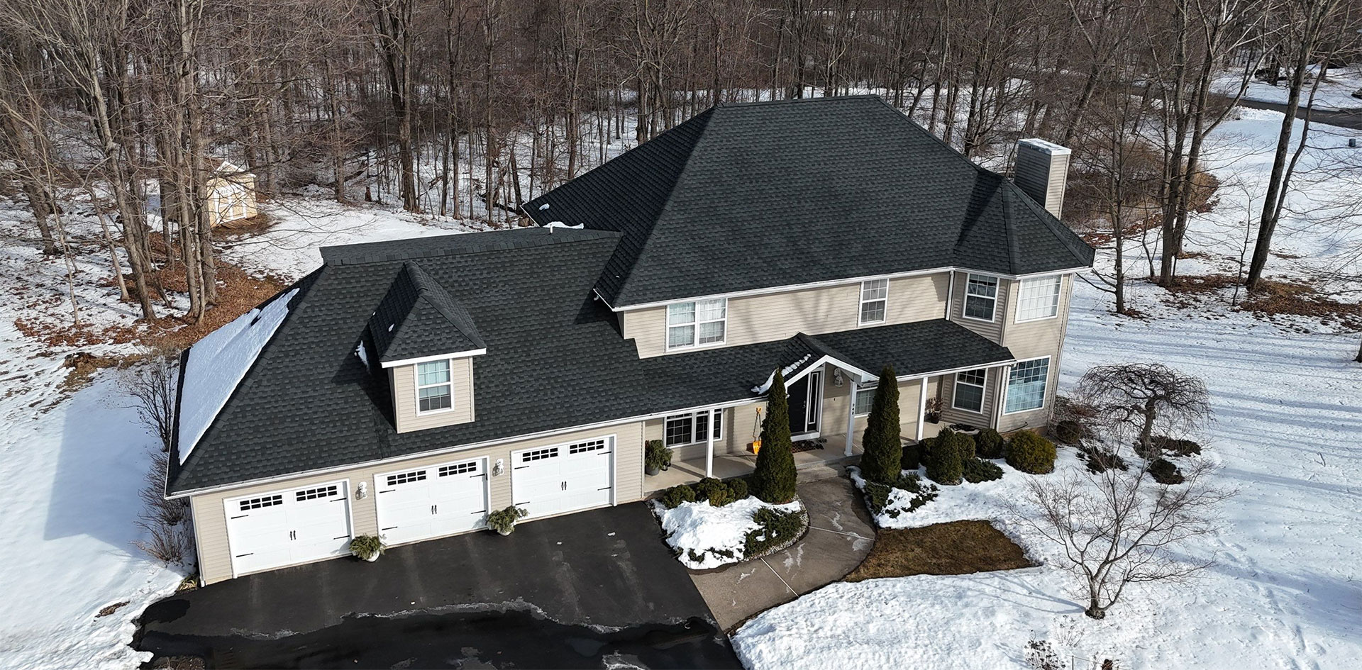 epic-roofing Aerial view of a home with a gray shingle roof and attached garage