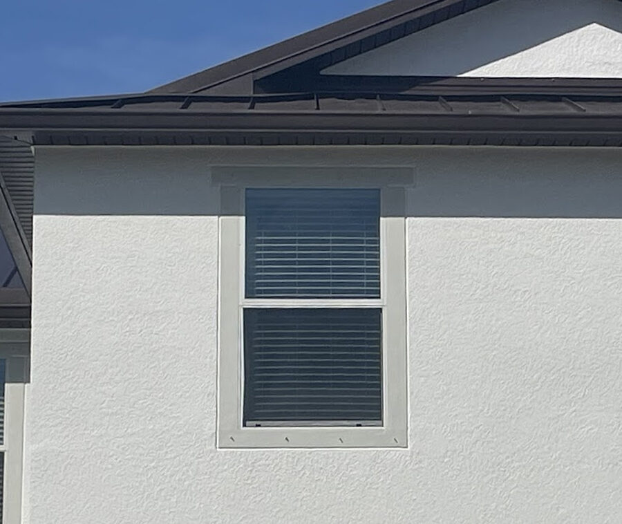 windows Newly installed window with white trim on a stucco wall