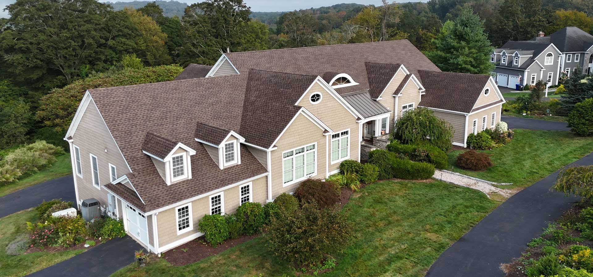 finished-roof-image Aerial view of a tan cape-style home with a finished gray roof